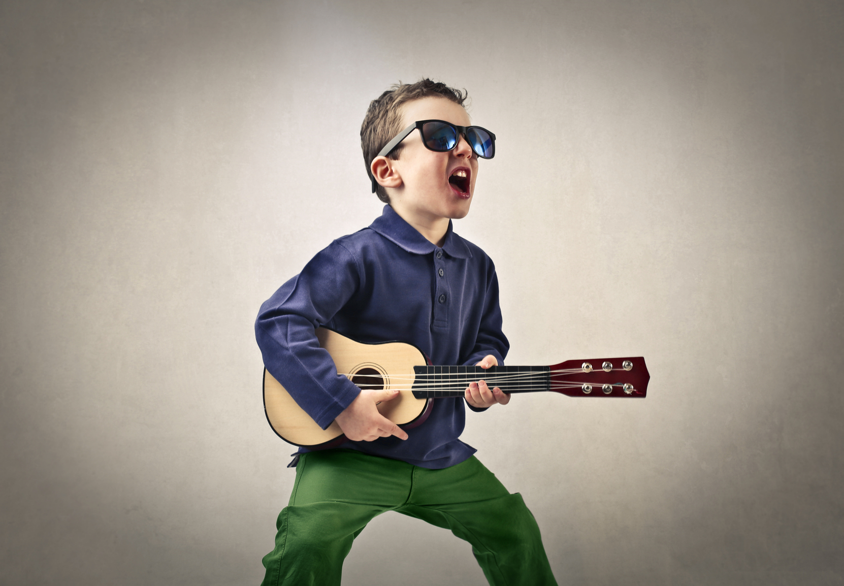 A kid singing enthusiastically with his little guitar